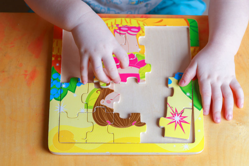 a child's hands putting a puzzle together