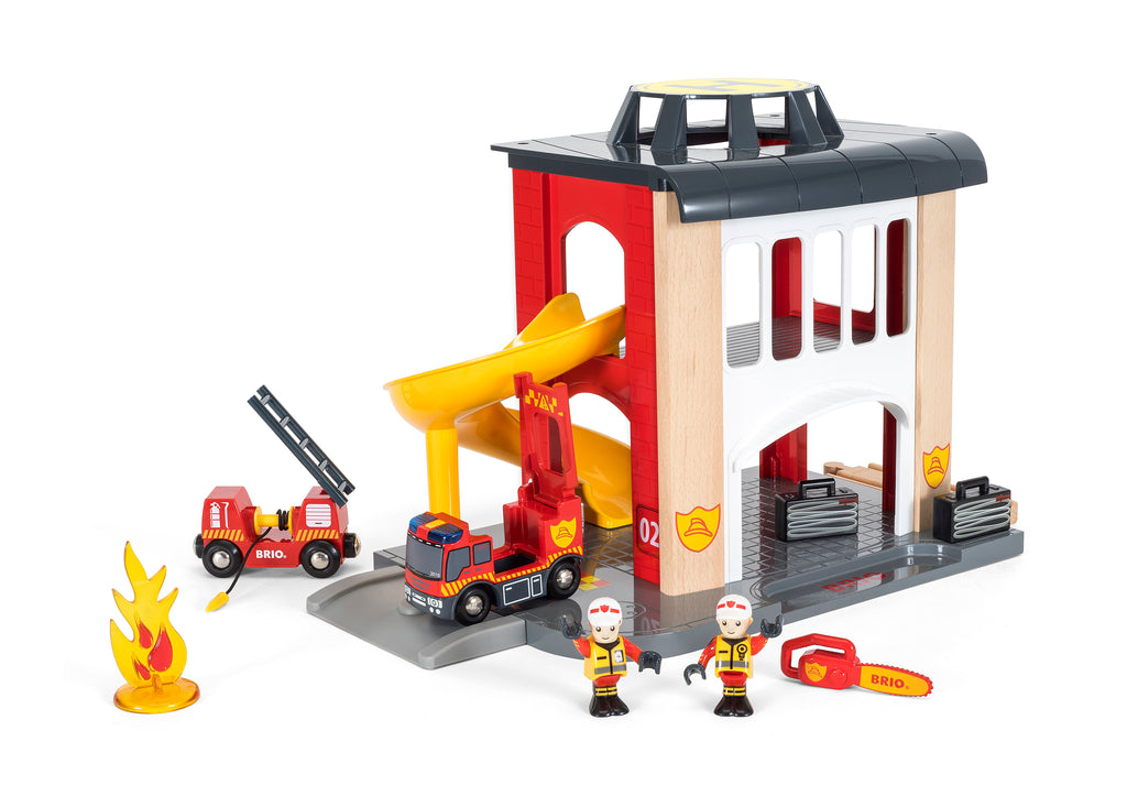 the red and white firestation with slide, lit up fire truck, a second firetruck, a chainsaw, plastic fire, and two firefighters
