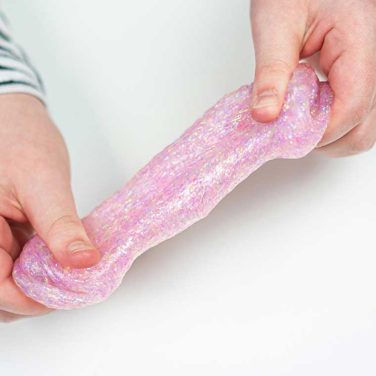 two hands stretching the glittery pink putty