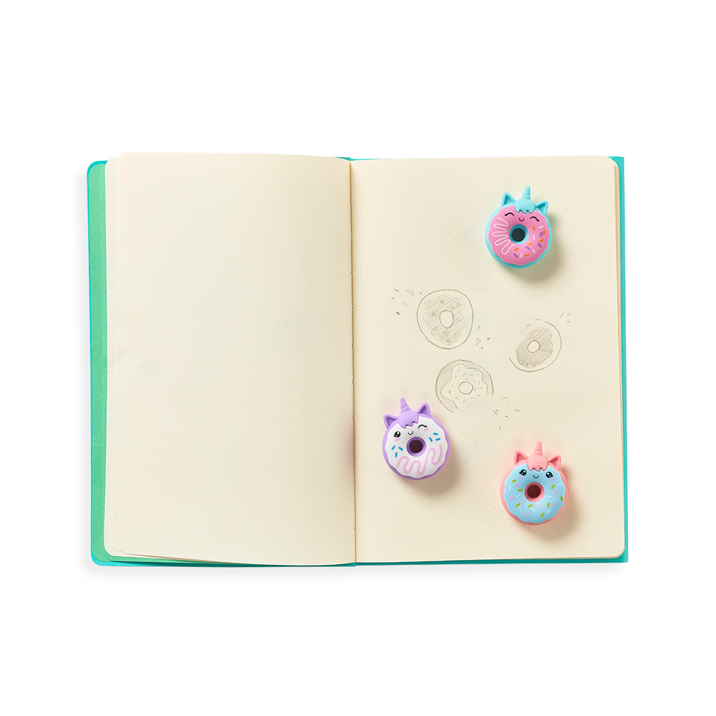 three unicorn donut erasers on a sketch pad