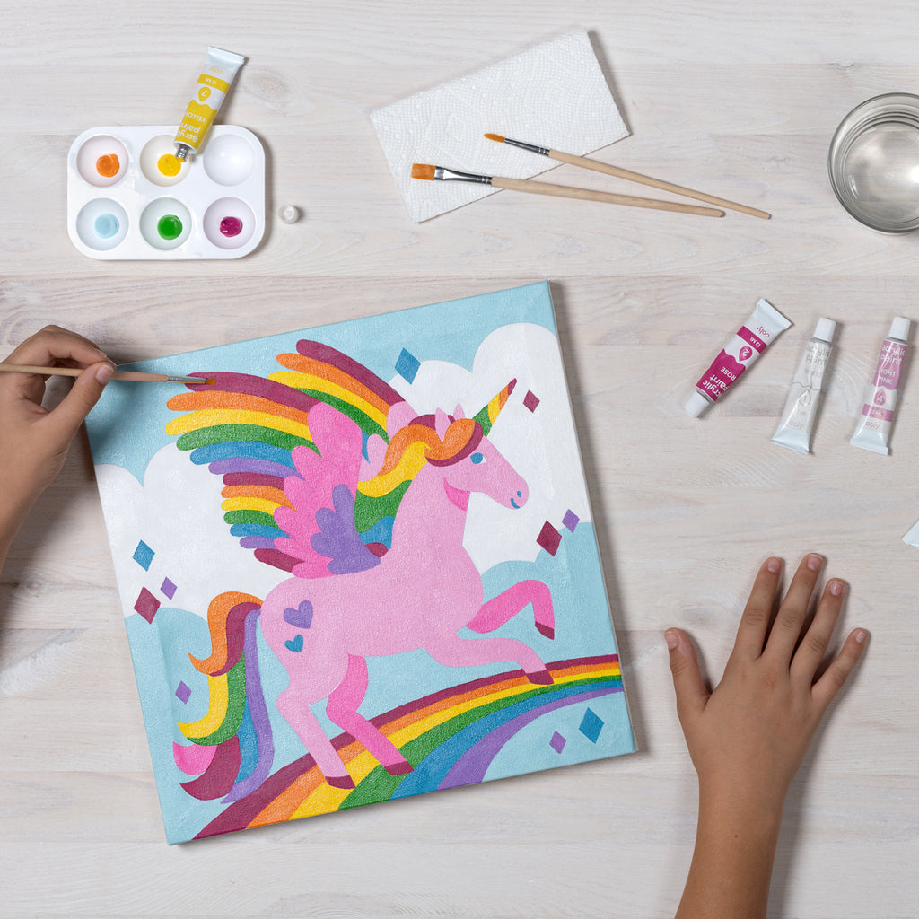 a child painting on the canvase with a colorful unicorn