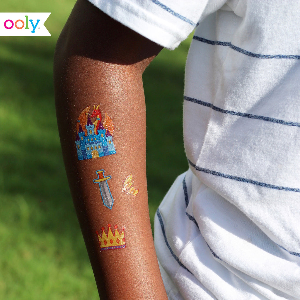 a boys arm with temporary tattoos of a dragon, a castle, a crown, and a sword