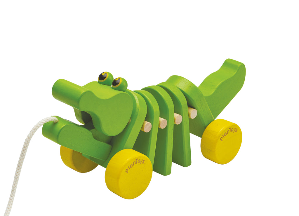 the green wooden aligator on wheels with a cord coming out of it's mouth