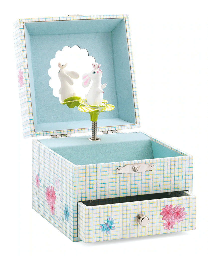an open light blue music box with a drawer and a rabbit sitting on a flower