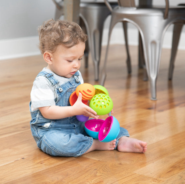 photo of child playing with multicolored tethered balls